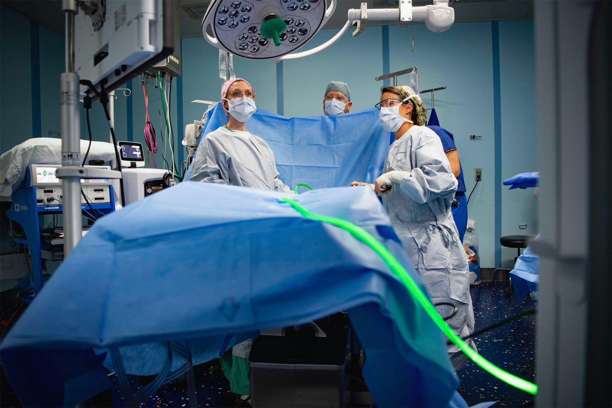Operating room team preparing the sterile field around a draped patient